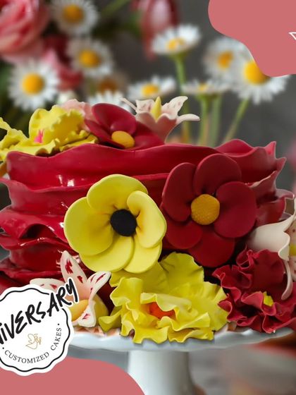 A bold and artistic floral cake for an anniversary in Lado Sarai. The vibrant red ruffles are adorned with bright yellow and red sugar flowers, creating a striking and memorable design.