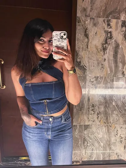 A mirror selfie in a full denim look. This trendy outfit features a denim halter top with a zip detail and matching high-waisted jeans.