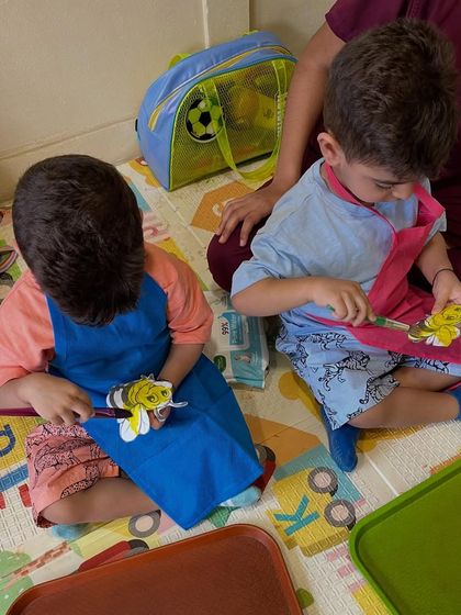 Two friends working side-by-side on their bee-themed crafts. My classes encourage social interaction and shared creative experiences for toddlers.
