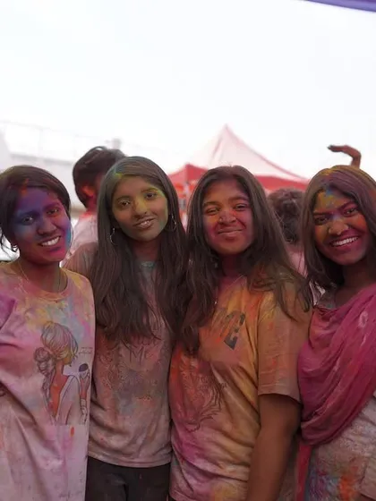 A group of friends smiling for the camera, covered in Holi colors. We love capturing the happy faces at our events.
