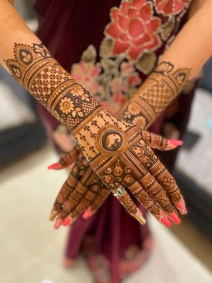 A beautiful example of matching bridal mehandi on both hands. The design features intricate bands, floral patterns, and a central circular motif with an elephant, all coming together for a symmetrical look.