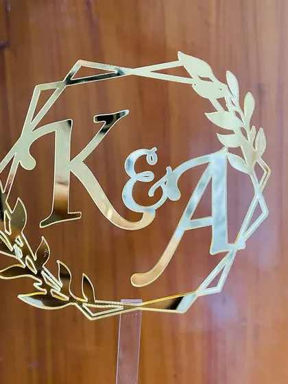An initial topper with "K&A" inside a geometric and floral frame, offering a modern twist on a classic design.