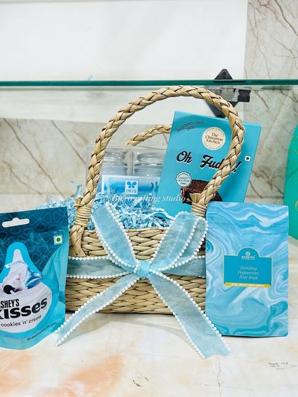 The new mom hamper, perfectly assembled with blue paper shred, Hershey's Kisses, fudge, and skincare, ready to be gifted.