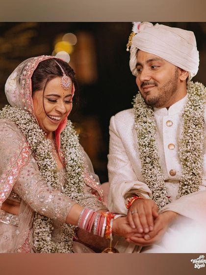 A single, beautiful shot of the couple holding hands during their pheras, their expressions full of joy.