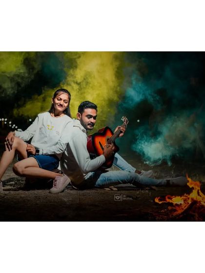 A cool and edgy pre-wedding shot with a couple by a campfire, with the groom playing guitar and colourful smoke bombs in the background.