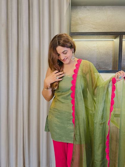A close-up on the delicate details of this suit. The fuchsia scallop border provides a beautiful contrast against the olive green, making it a unique and eye-catching piece.