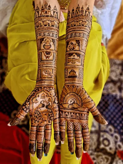 A beautiful and balanced traditional design extending to the elbows. The artwork includes temple domes, sacred kalash, and other auspicious symbols for the bride.