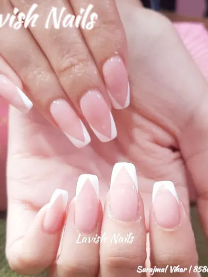 A modern V-shaped French manicure with crisp white tips on long coffin nails.