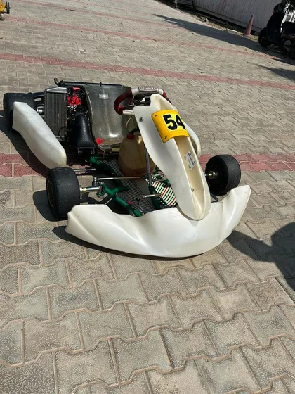 A white kart on a stand in the paddock.