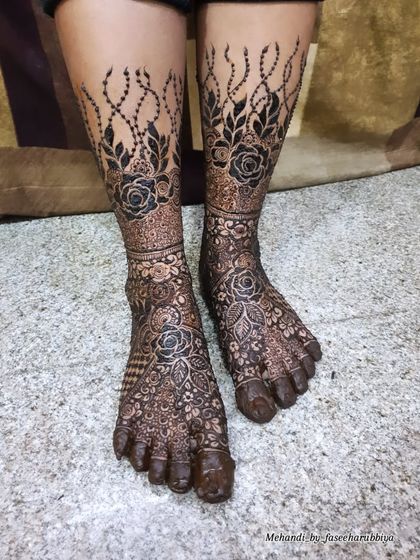 A full view of Neha's bridal leg mehendi, featuring bold roses and delicate vine-like chains.