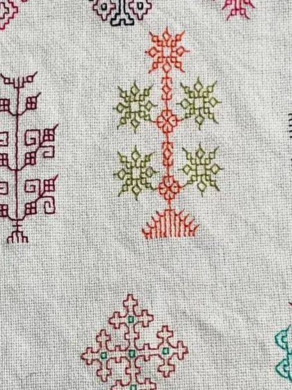 A close-up of a Kasuti sampler, showing the variety of 'ganti' (line stitch) and 'murgi' (zig-zag stitch) used to create complex patterns like trees and architectural forms.