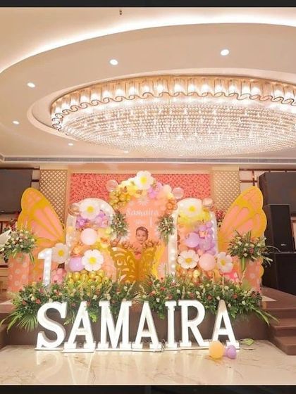 The final look of the grand stage, featuring large butterfly wings, marquee letters, and a mix of balloons and fresh flowers.