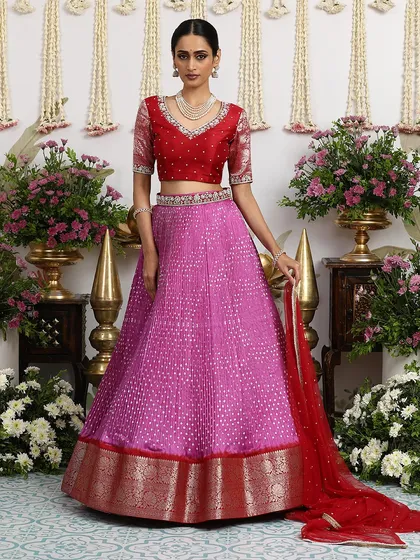 A stunning pink Bandhani lehenga paired with a classic red embroidered blouse. The color combination is both traditional and refreshingly modern.