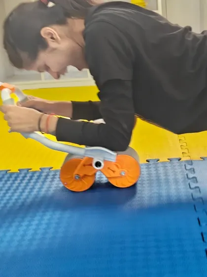 A student strengthens her core and upper body using an ab roller, demonstrating the focus and determination we cultivate in our fitness sessions.