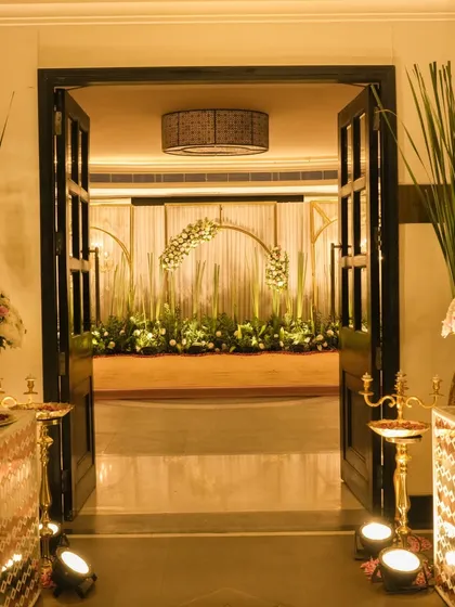 The entrance to a grand celebration, framed by tall banana plants and elegant mirror consoles. This view promises a stunning decor experience right from the moment guests walk in.