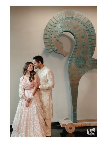 An elegant portrait of a couple during their Roka ceremony, posed next to a modern art sculpture. This shot blends traditional celebration with contemporary style.