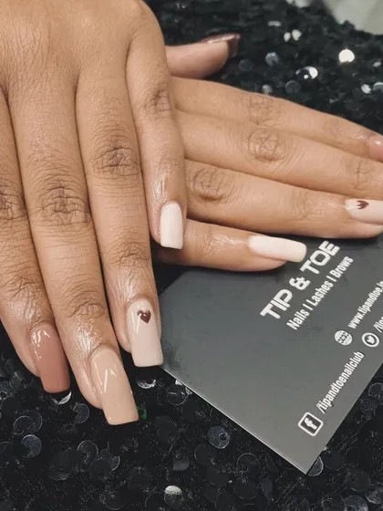A subtle and sweet design. This manicure features various shades of nude with a tiny heart accent, proving that sometimes the smallest details make the biggest impact.