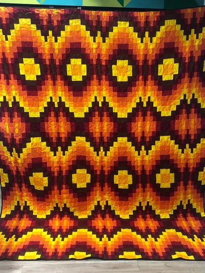A showcase of bold, modern design. This Bargello quilt uses a special piecing technique to create a sense of movement and depth with its vibrant, fiery colors, demonstrating our skill in contemporary quilt patterns.