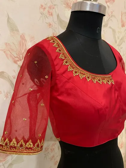 A simple and elegant red blouse with sheer net sleeves. The neckline and cuffs are finished with a delicate gold embroidered border.