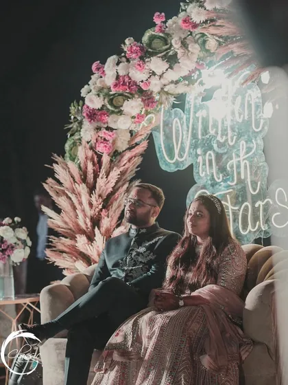 The couple enjoying a quiet moment at their Sangeet. The soft glow of the neon sign and the lush floral decor create an intimate and romantic atmosphere.