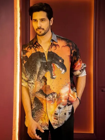 A close-up portrait of Sidharth Malhotra. The warm tones of the shirt and the background create a cohesive and visually appealing image for this promotional shoot.