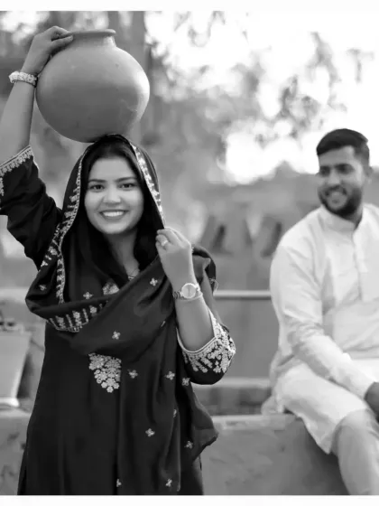 Another shot from the village-themed pre-wedding session. The bride playfully carries a pot on her head, adding a touch of traditional charm and authenticity to their love story.