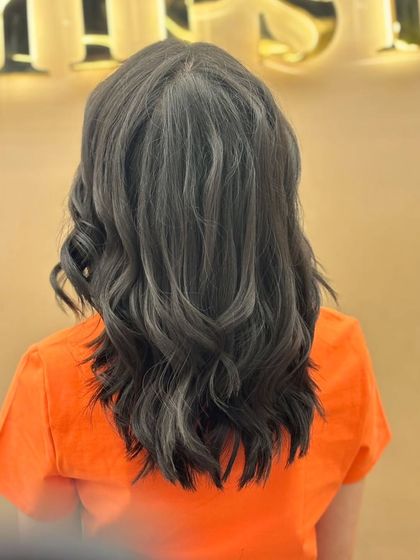 A back view of a client's hair with a deep, uniform color and subtle grey blending. The soft waves add a touch of elegance to this modern and sophisticated style.