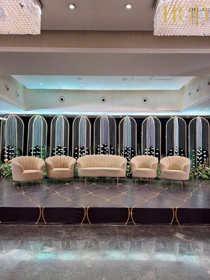 A modern and chic reception stage with a backdrop of arched panels and hanging crystal strings, complemented by stylish, contemporary seating.