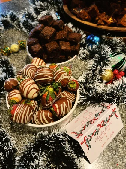 A festive dessert spread for a Christmas party, featuring chocolate-dipped strawberries and rich brownie bites. These are perfect, easy-to-eat treats for any celebration.