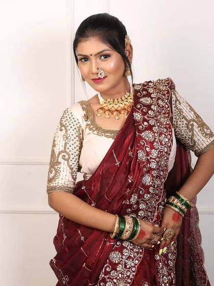 A rich maroon velvet Nauvari saree paired with a cream-coloured, heavily embroidered blouse. This is a luxurious option for a winter wedding.