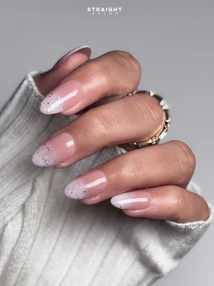 A beautiful variation of the French manicure, this is a glitter fade or "glitter ombre" tip. The silver glitter is concentrated at the tip and fades softly into the nude base.