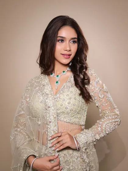 This portrait captures the elegance of the entire ensemble, from the intricate embroidery on the blouse to the sparkling diamond and emerald jewelry.