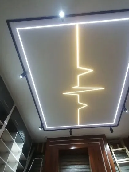 A commercial or retail space ceiling featuring a heartbeat-shaped profile light within a larger illuminated rectangle. The track lights on the side provide flexible, focused lighting.