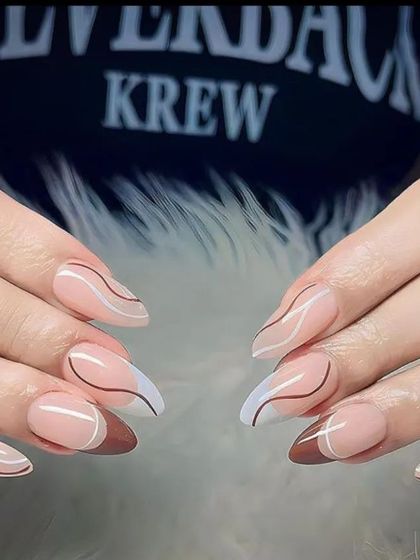 A modern and chic design with abstract brown and white lines on long, pointed nails.