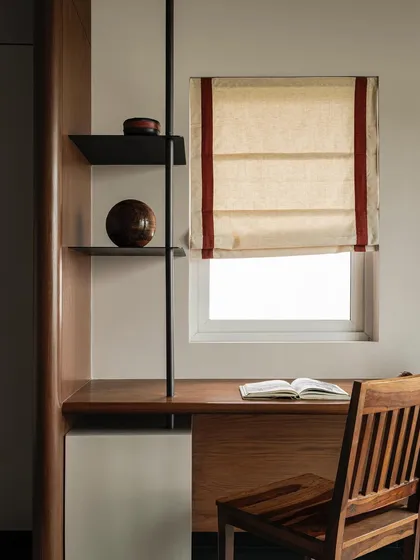 This study nook in Apartment 1005 is a perfect example of efficient and elegant design. A simple wooden desk is framed by a curved wall partition, with a linen roman blind adding a touch of softness and warmth.