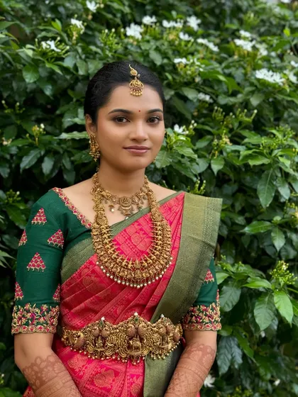 A classic portrait of Ragavi against a lush green background. Her makeup is flawless, and her traditional attire creates a timeless and beautiful bridal image.
