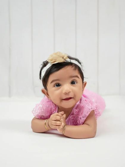 A bright-eyed and curious expression from this little one during her sitter session. The clean, white background keeps the focus entirely on her adorable face and personality.