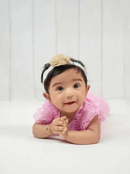 A bright-eyed and curious expression from this little one during her sitter session. The clean, white background keeps the focus entirely on her adorable face and personality.