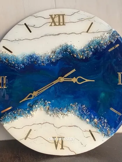 A beautiful geode clock with a river of deep blue resin and silver accents flowing through a white base.