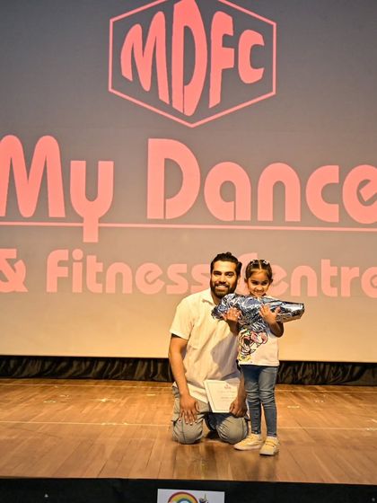 Anaira receiving her gift on stage, a sweet reward for her hard work and beautiful performance.