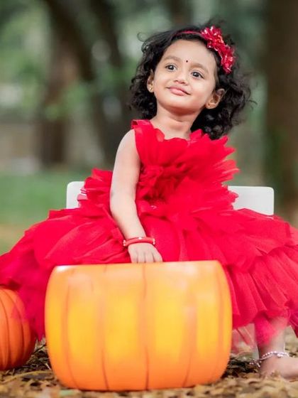 Too cute to be real. The vibrant red dress looks stunning against the natural, earthy tones of the park.