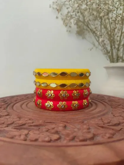 A bright and sunny set of handmade bangles in yellow and red. These are decorated with mirror work and floral sequin patterns, perfect for a Haldi or Mehendi function.