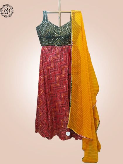Here is the complete Navratri ensemble, featuring the red patterned lehenga, green blouse, and a vibrant yellow leheriya dupatta. It's a full look, ready for you to step into the festive spirit.