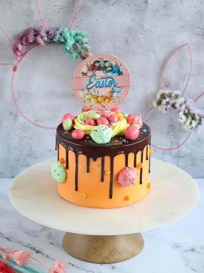 This vibrant Easter cake features a chocolate drip, colorful candy eggs, and a festive topper, making it a joyful centerpiece.