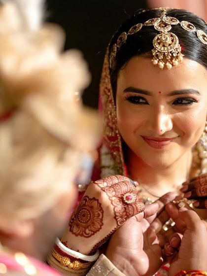The bride's gentle smile as she looks at her groom during the wedding rituals, a moment of quiet connection.