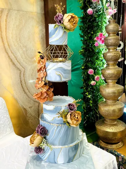 A stunning five-tier wedding cake with a beautiful blue marble effect and gold accents. The floating tiers in the middle add a modern, architectural element, making it a true work of art.
