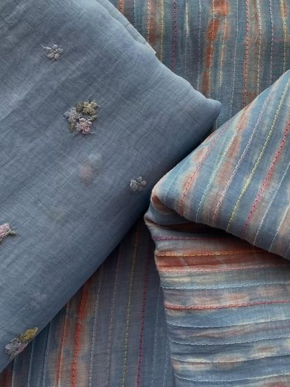 This set of Mul Chanderi fabrics in a dusty blue features one with delicate floral embroidery and a coordinating striped and tie-dyed piece.