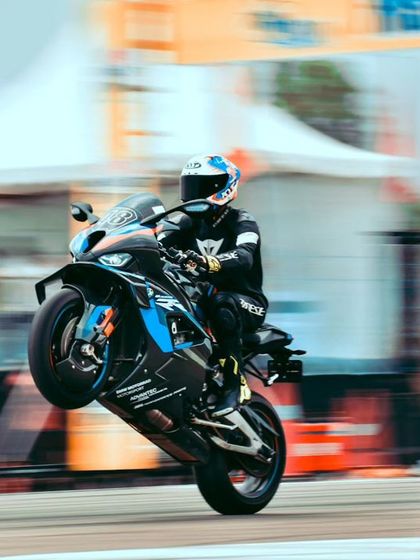 A rider on a BMW superbike performs a rolling wheelie, a high-speed maneuver that is both thrilling and technically difficult.