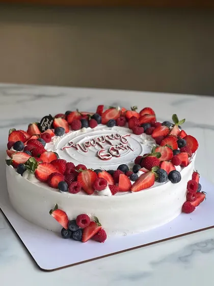 A 60th birthday cake overflowing with a mix of fresh strawberries, blueberries, and raspberries. Berry-loaded cakes are always a popular choice, especially in the winter.
