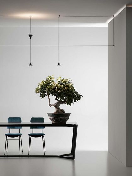 The Filomena system stretched across a long dining table, its thin black lines creating a subtle yet effective architectural statement.